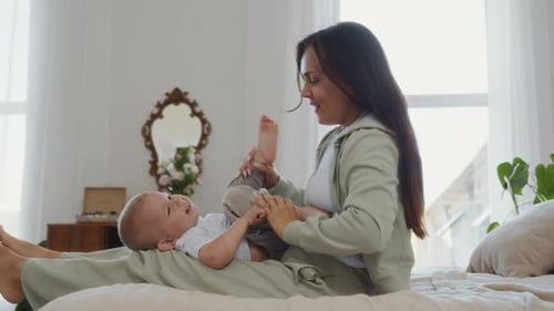 Woman Playing with Baby on Bed in Bright Room
