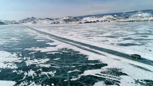Aerial View on a Car Driving on an Ice Road on Frozen Baikal Winter Landscape of Lake Baikal Drone