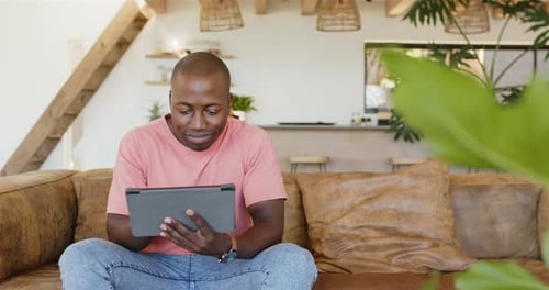 Smiling Man Using Tablet on Couch at Home