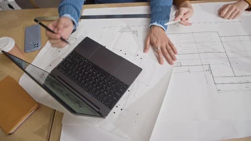 Des membres de l'équipe diversifiés travaillent ensemble sur un ordinateur portable et un plan d'étage au bureau
