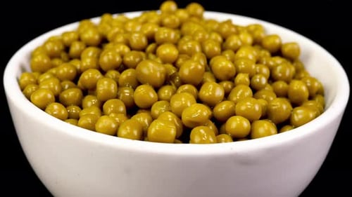 Marinated pickled sweet green peas with white bowl rotate background.