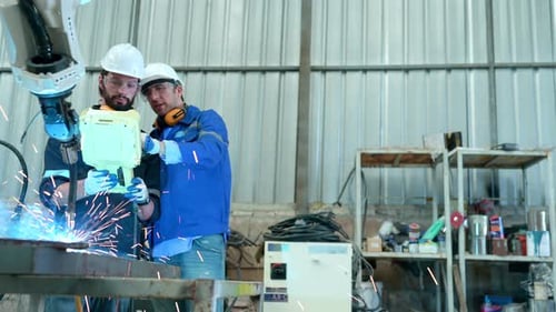 Beide Ingenieure manipulieren die Hand eines Schweißroboters