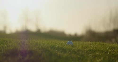Golf club hitting ball on green grass