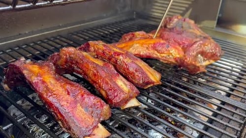 Checking The Internal Temperature Of BBQ Ribs On A Smoker.