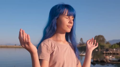 Teen Meditates by Lake With Blue Hair