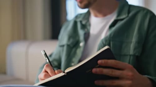 Man Hand Making Notes in Copybook Listening Online Webinar Studying on Laptop