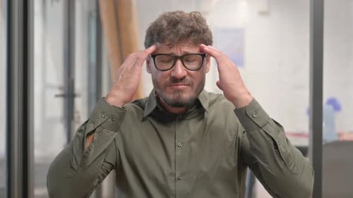 Portrait of Middle Aged Man with Headache in Office