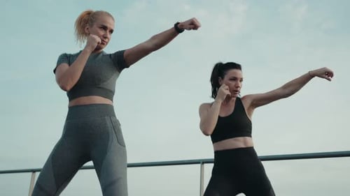 Mujeres atléticas que boxean al aire libre en sincronía