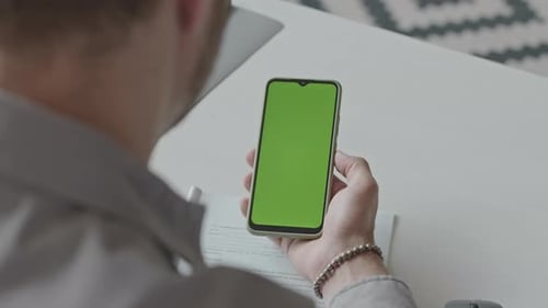 Man Using Smartphone with Green Screen at Workplace