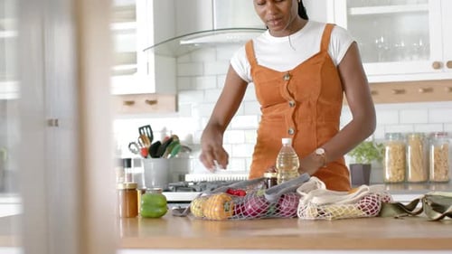 Desempacando verduras y botellas, mujer preparando la comida en la cocina