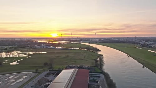 Aerial sunset drone shot passing over industrial area with impressive windturbines and bridge on the