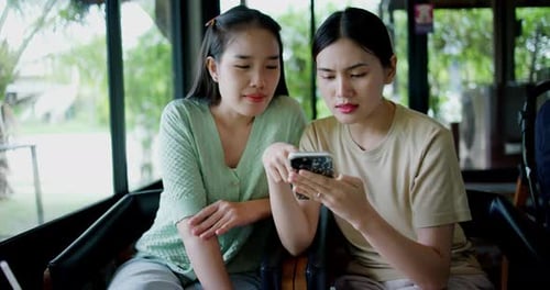 Two Women Looking at Smartphone in Cafe