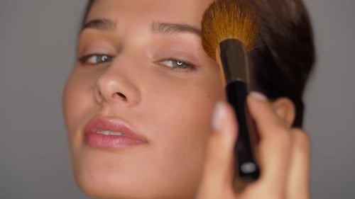 Beautiful Woman Applies Makeup with a Brush