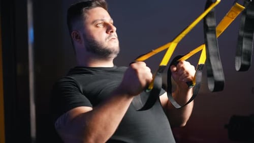 Starker junger Mann beim Training mit Trx-Trageriemen zum Ganzkörpermuskeltraining