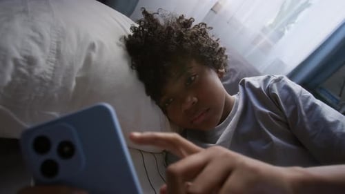 Child Using Mobile Phone Lying on Bed