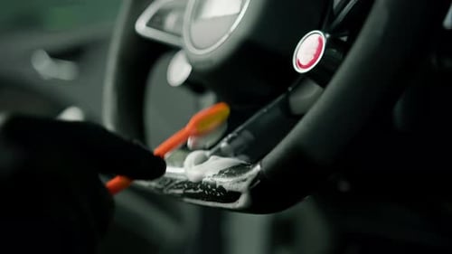 Worker cleans steering wheel professional brush and clout of microfiber Professional car wash