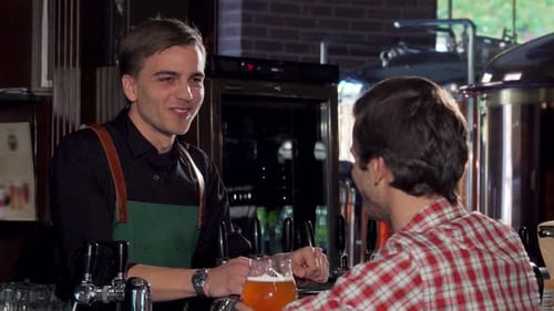 Joyful Man Enjoying a Beer While Chatting with a Friendly Bartender at a Cozy Pub