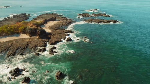 Rocky shoreline surrounded by turquoise water and small sandy beaches from above