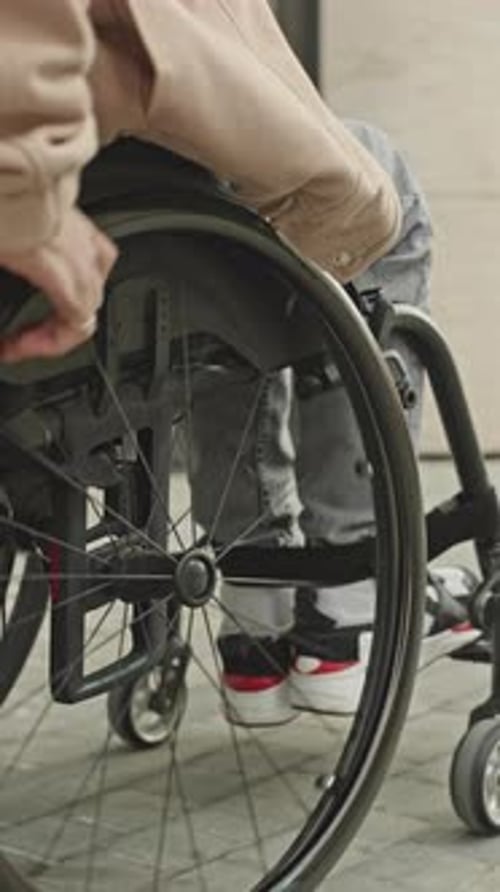 Close Up View of Man Riding Wheelchair along Urban Street