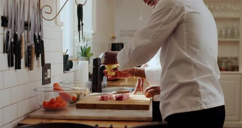 Chef seasoning steak with pepper in bright kitchen