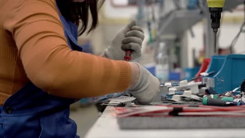 Travailleur technique de l'atelier de production. Un technicien en gants attache des pièces à la base métallique