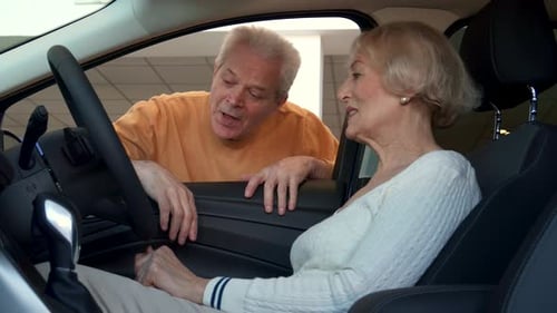 Couple de personnes âgées explorant les caractéristiques d'une voiture