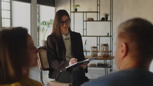 Family Psychologist in Glasses is Listening to Her Patients and Making Notes in Notebook
