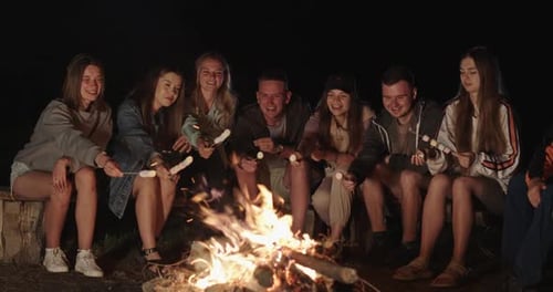 A Group of Friends Happily Spend Time Around a Campfire in the Forest at Night Warm Summer Time