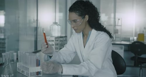Woman Scientist Examines Test Tubes in Lab