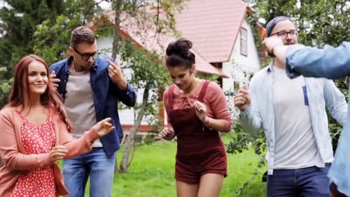 Happy friends dancing groovy music together at summer garden party