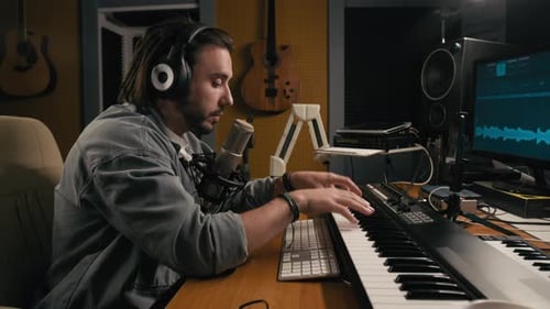 Male Composer Playing Synthesizer and Speaking into Microphone on Podcast