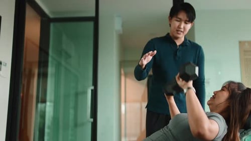 Personal Trainer Helping a Woman Lift Dumbbells at the Gym