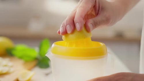 Fruits, stay-at-home parent enjoys squeezing lemon juice in housewife's home kitchen. Close-up