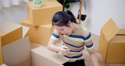 Woman Packing Belongings Into Cardboard Box at Home