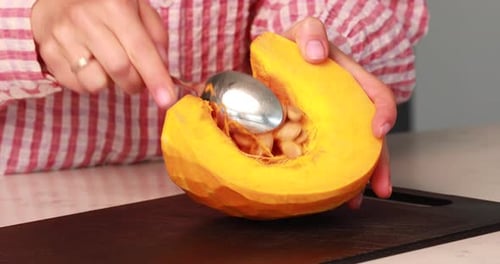 Woman scooping seeds from a pumpkin