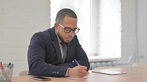 Focused Man Writing in Office Environment