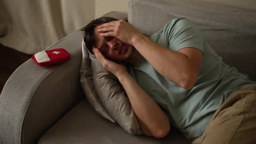 Man Lying on Couch Suffering from a Headache