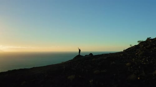 Hiker Man Enjoys Ocean View at Top of Mountain Hands Up in the Air