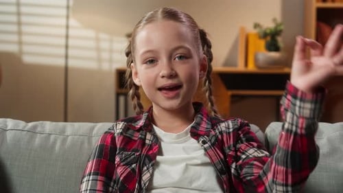 Girl Gives OK Hand Gesture on Sofa