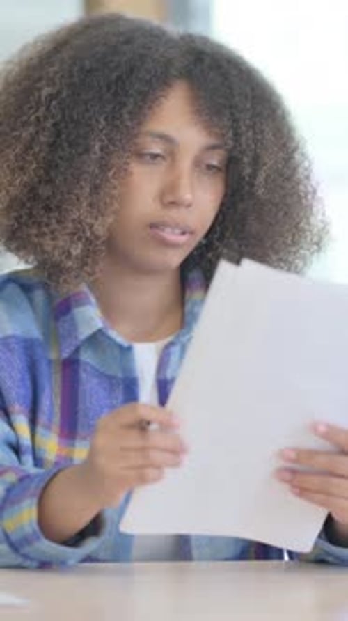 Young Woman Reads Documents at Table Indoors