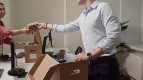 Woman Helping Colleague with Box Unpacking when Arranging Workplace in Office