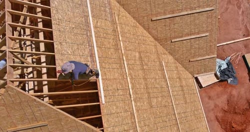 Un techador instala un revestimiento de madera contrachapada y enmarca una nueva estructura de vivienda