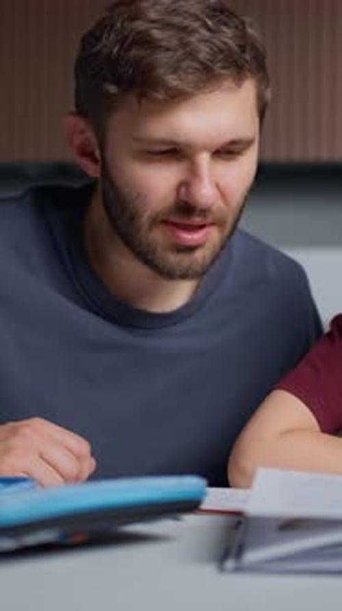 Young Man in Casual Clothing Focused and Engaged While Studying or Working on Documents and