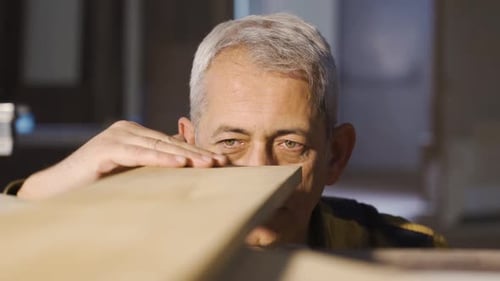 Carpenter man examines and touches wood in a carpentry workshop.