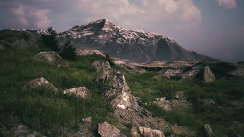 Snow Capped Peak Towers Over Rocky Hillside in Daylight
