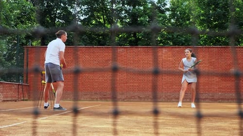 Girl Practicing Tennis Swing with Coach