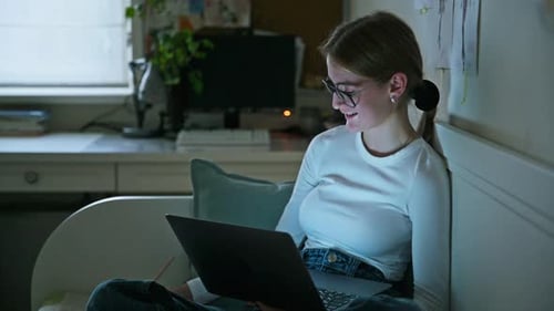 Young Adult Using Laptop on Bed at Night