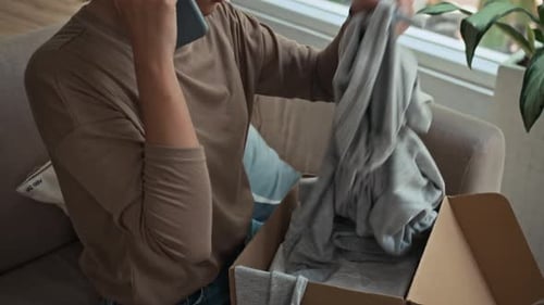 Woman on Phone Opening Box of New Clothes