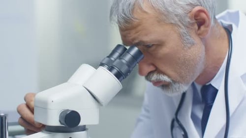 Senior Scientist Using Microscope in Bright Laboratory