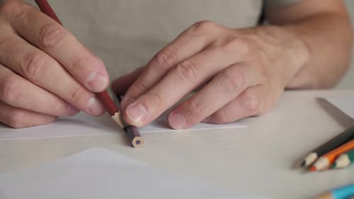 Man Sharpening a Colored Pencil with Another Pencil